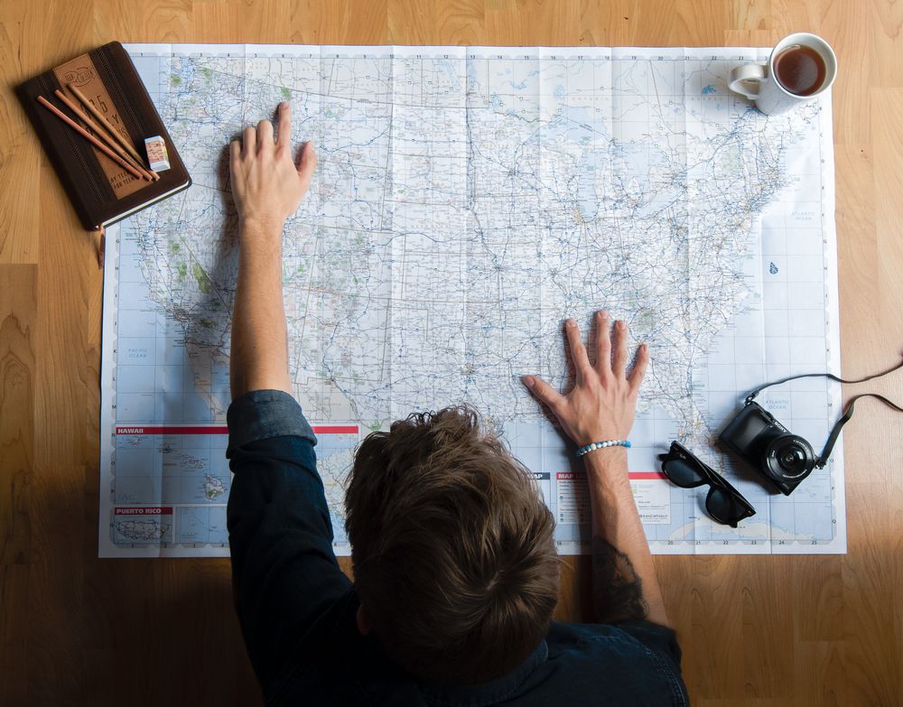 Pessoa debruçada sobre um grande mapa, planejando uma viagem
